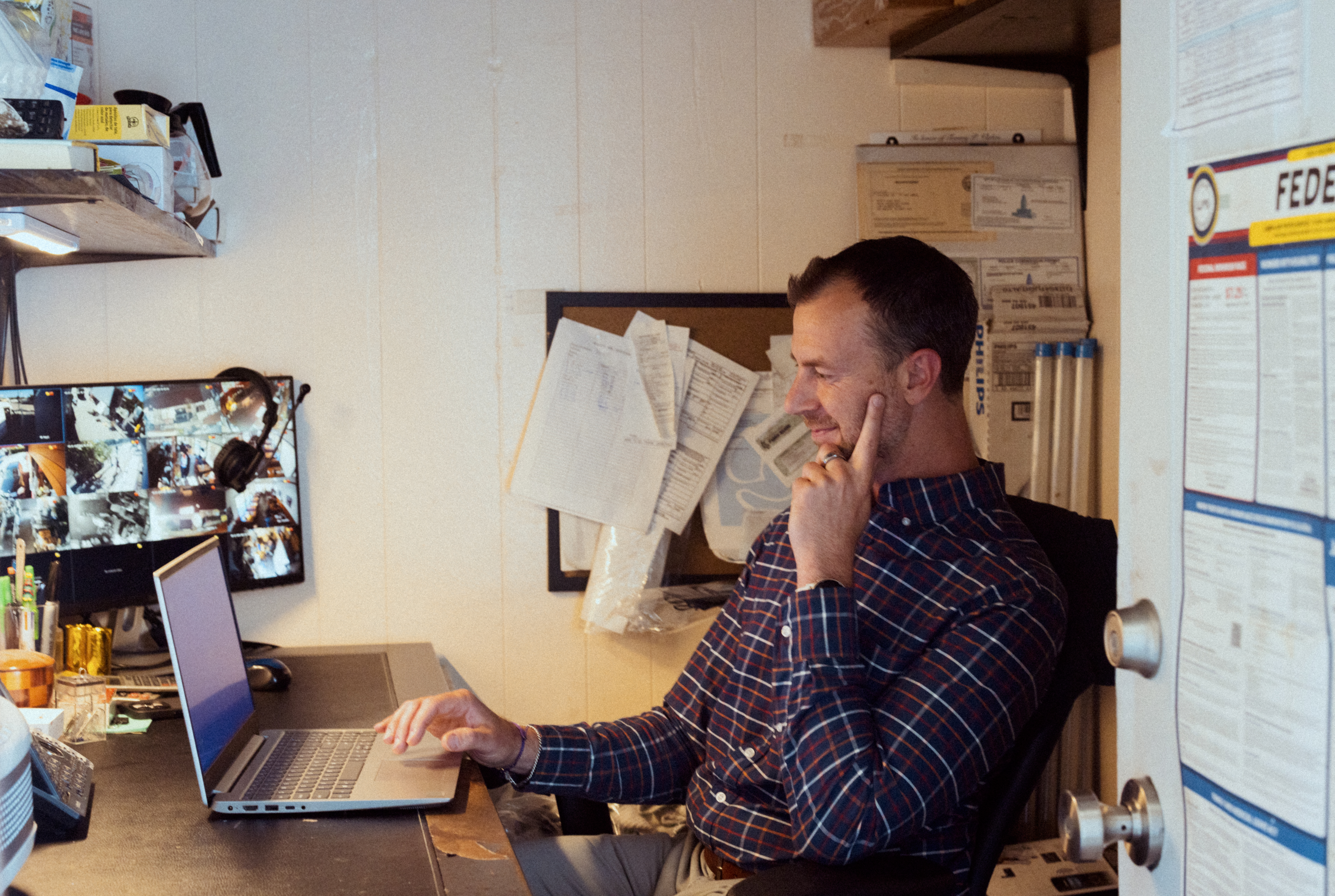 Operator at his desk talking on a phone, papers and monitors visible.